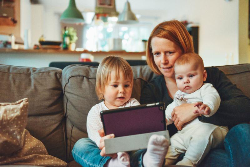A mother with two children video chatting on a tablet.