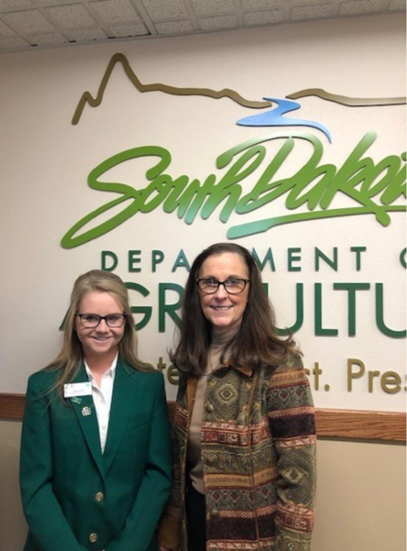 two women standing in front of a sign.