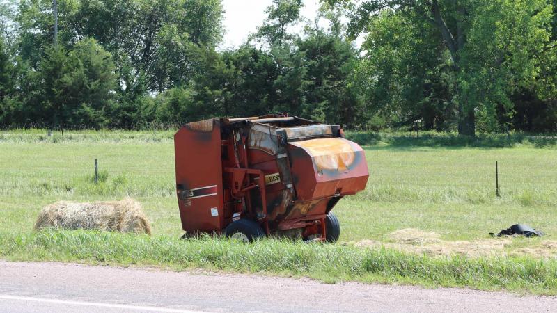A red, round hay baler that has been burned up from a fire.