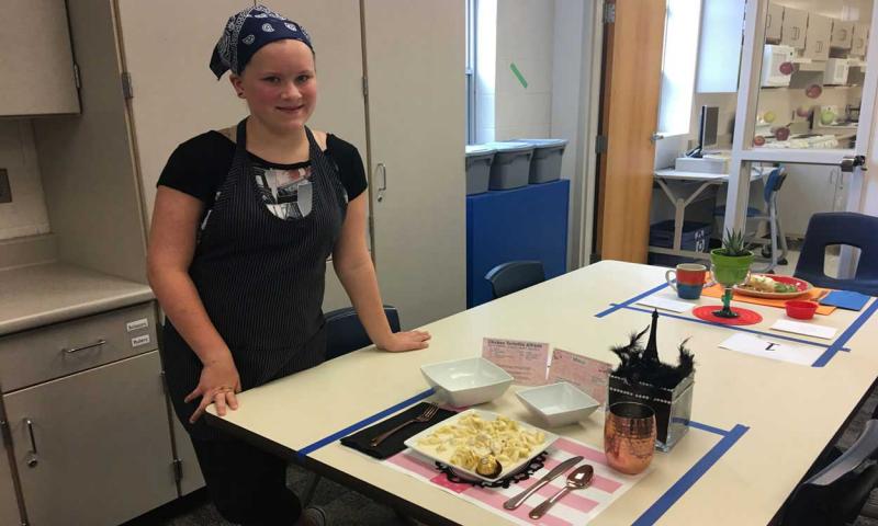 Ellie Wagner presenting an entrée and place setting in a kitchen.