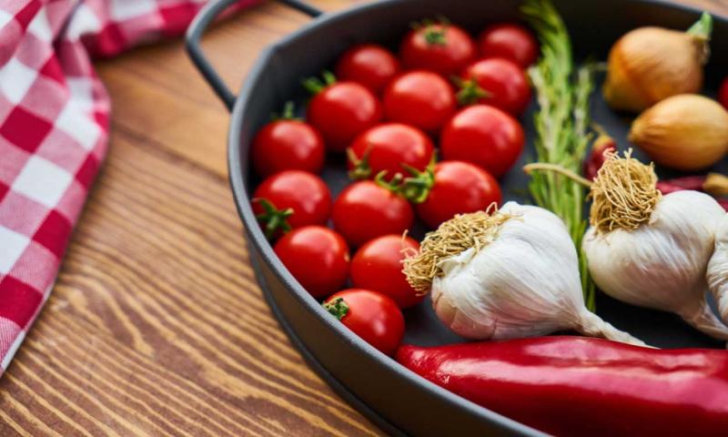A variety of fresh vegetables in a black skillet.