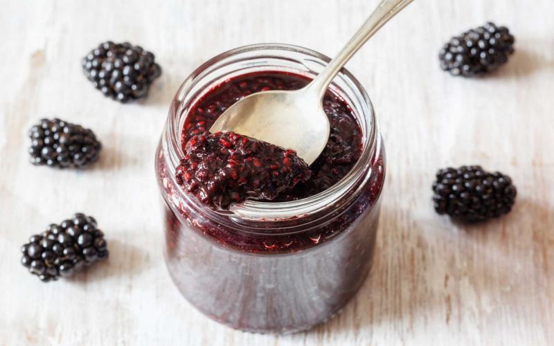 Jar of blackberry jam on countertop.