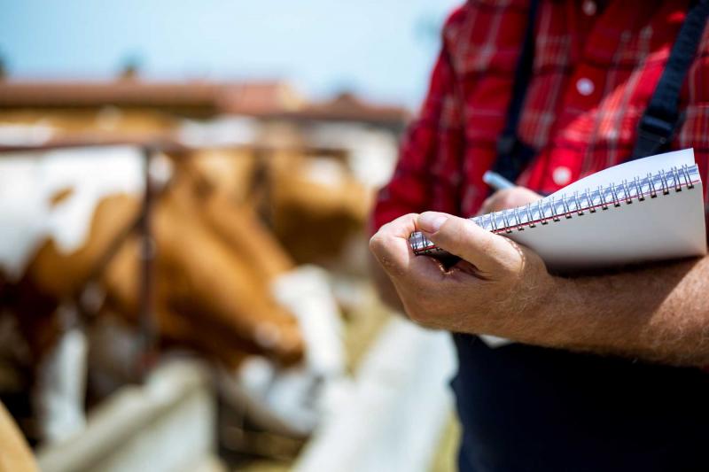 Rancher holding a notepad beside a feed bunk.