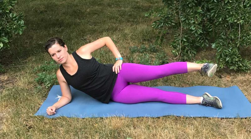 Young woman demonstrating the reclined side leg raise exercise. For a complete description, call SDSU Extension at 605-688-6729.
