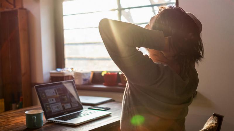 Young man stretching at a remote work station in his home.