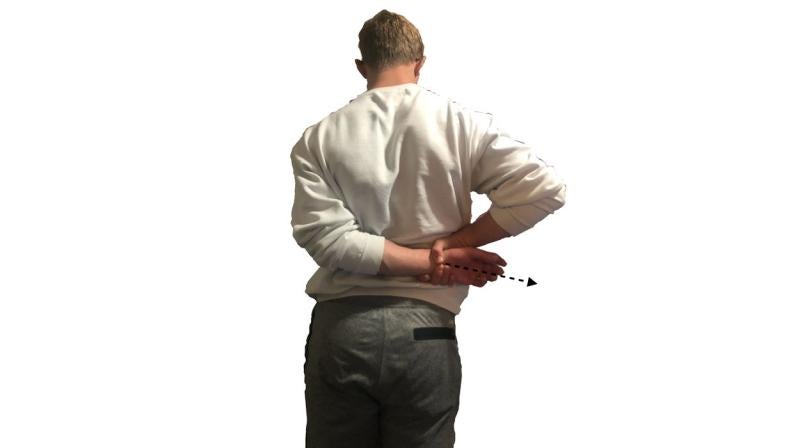 Young man demonstrating the standing shoulder stretch. For a complete description, call SDSU Extension at 605-688-4792.