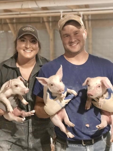 A man and a woman both holding piglets