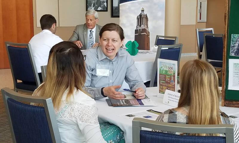 4-H volunteer discussing an exhibit with two 4-H youth.