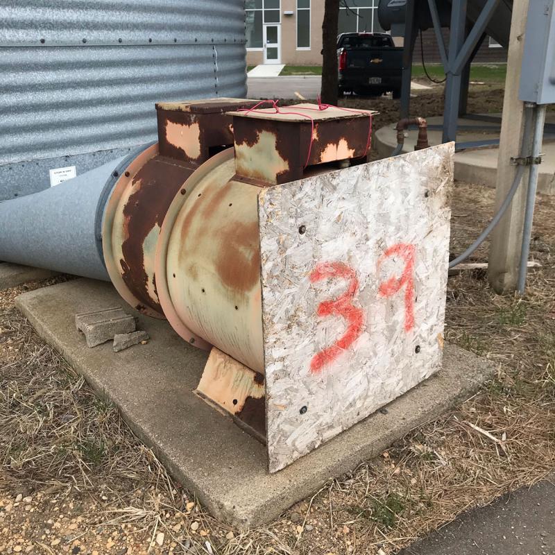 Grain bin fan with a plywood cover installed on the exterior.
