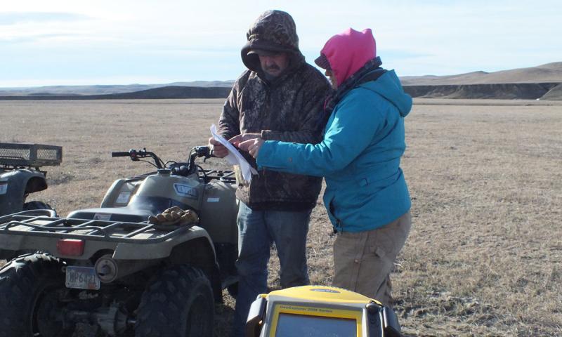 Two landowners revieiwng a grassland management plan in a field.