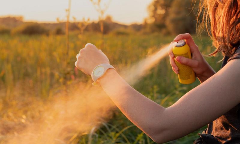 Young woman applying insect repellant before an evening hike.