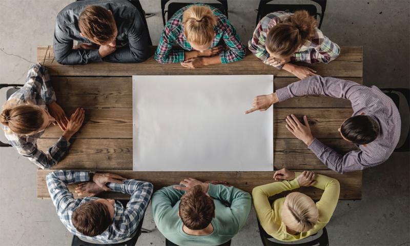 Small group of young professionals gathered around a meeting table.