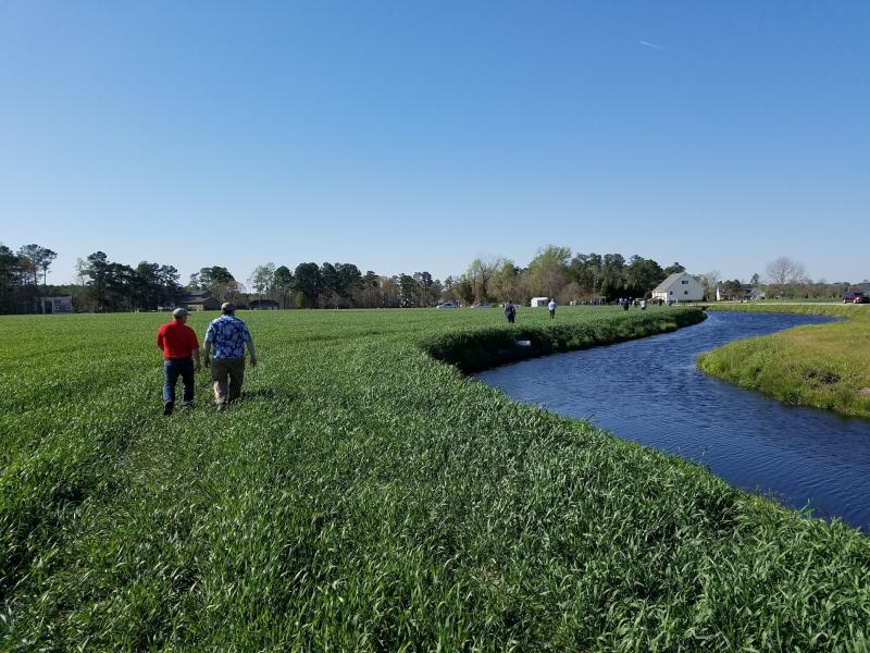 Two men walking near a drainage water recycling pond