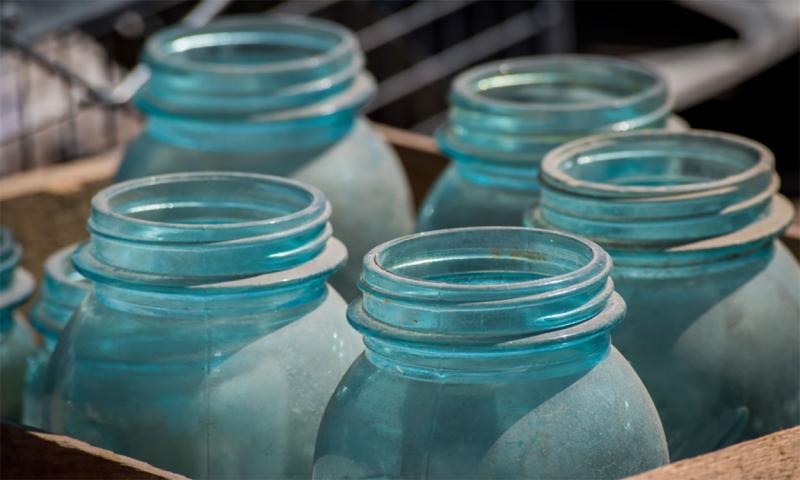 Blue-tinted antique canning jars in a brown box.