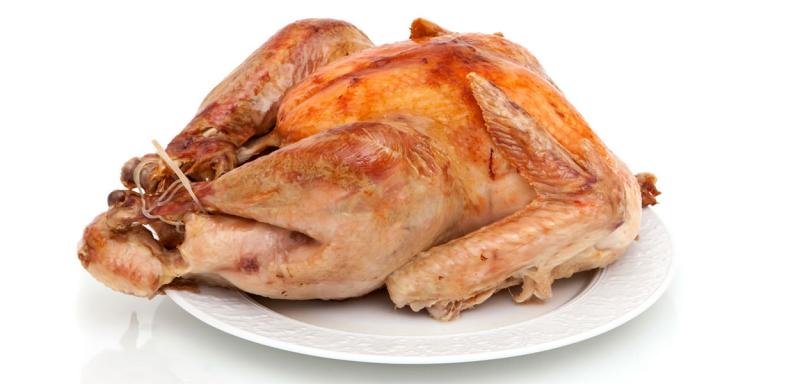 Whole turkey resting on a white, glass plate.