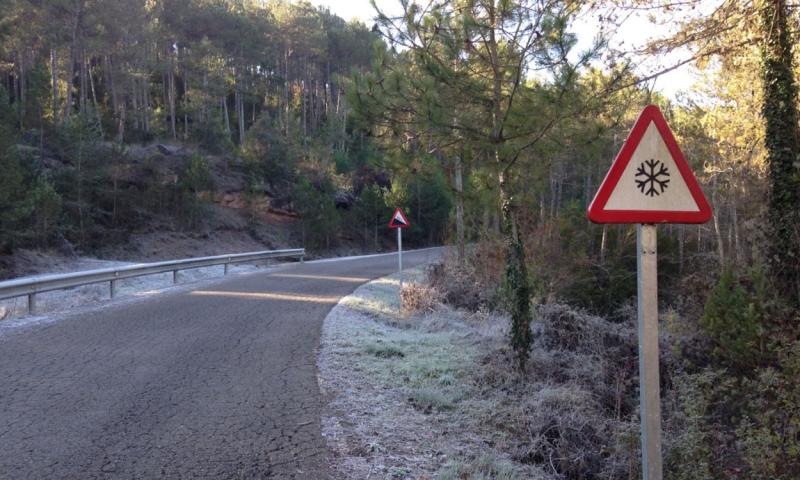 Winding road with a warning sign for winter conditions.