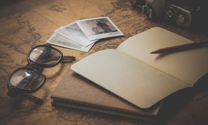 A blank notebook sitting by eye glasses and photos.