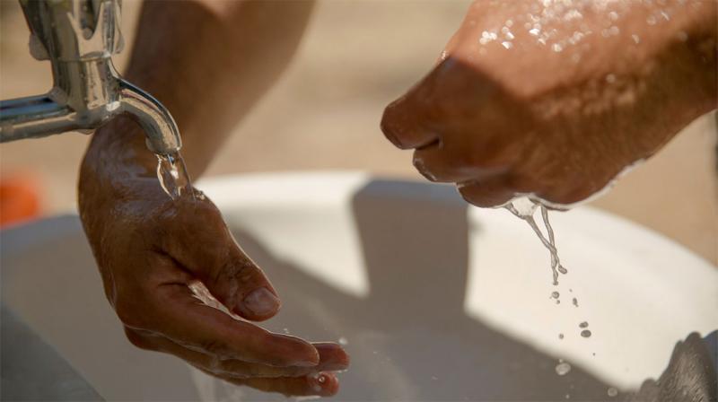 Man washing hands at an outdoor sink.