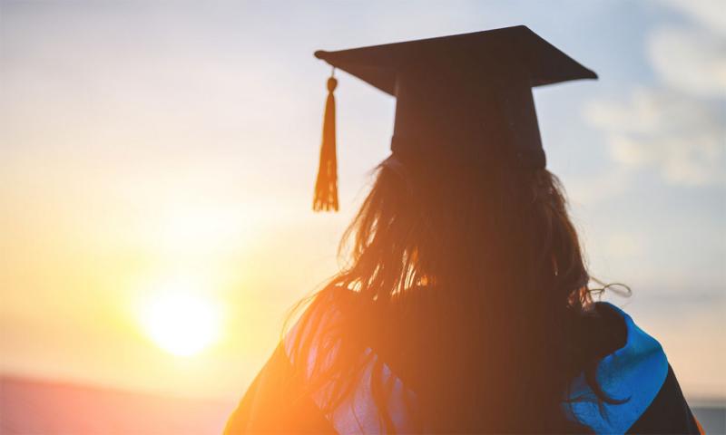 High school graduate watching a rural sunset.