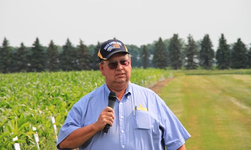 Paul O. Johnson giving a presentation near a research plot.