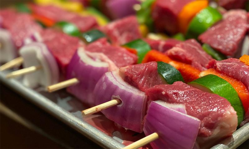 Beef kabobs and vegetables on wooden skewers.