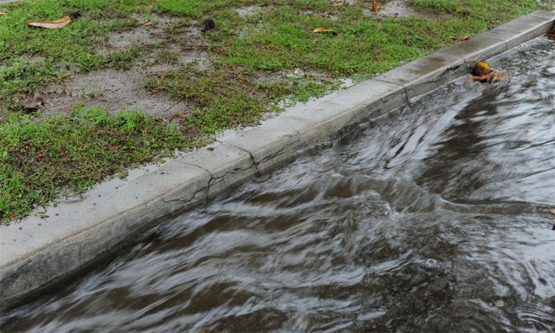Storm water rushing down a street gutter.