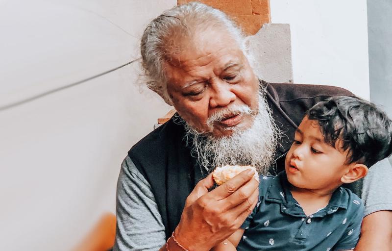 A grandfather offering his grandson food