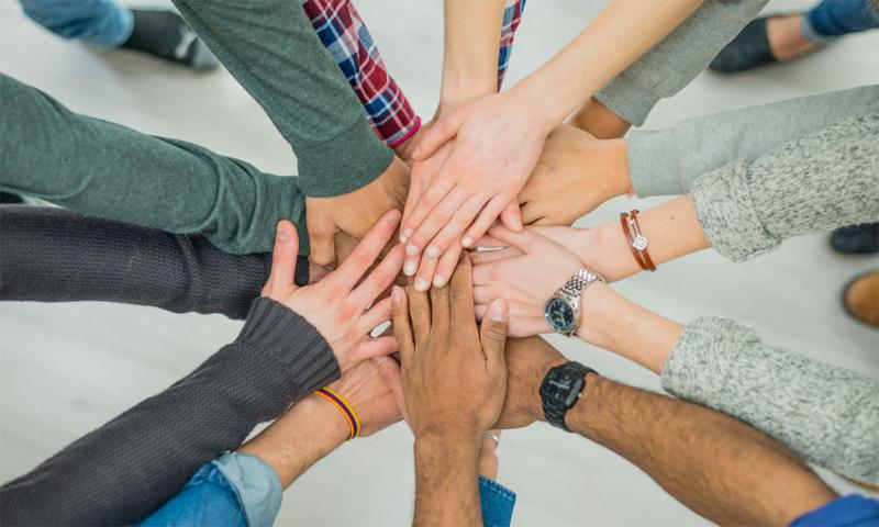 Diverse group of community members putting their hands together.