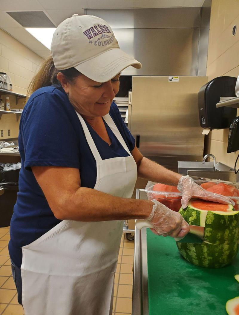 Dawn Johnson preparing watermelon in a school kitchen.