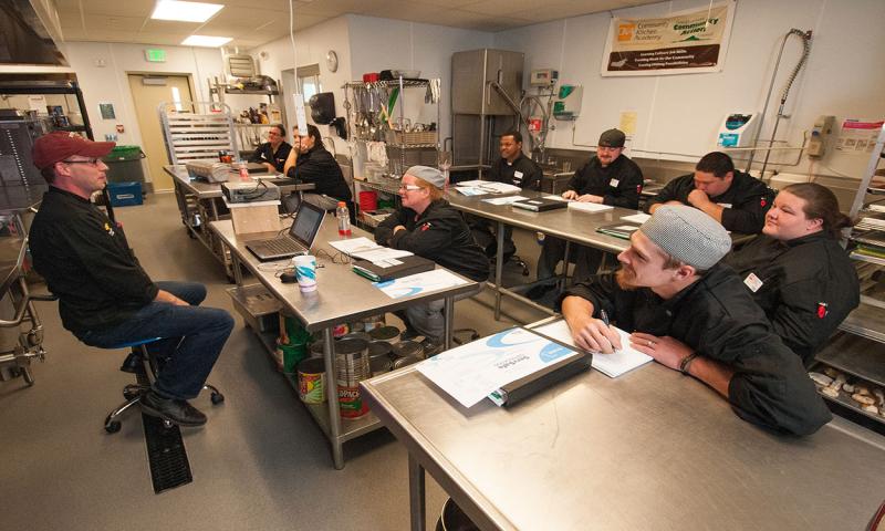 Group of cooks participating in a training course in a commercial kitchen.