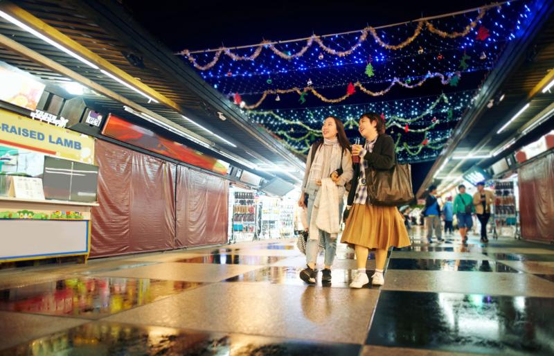 Two women shopping at a holiday food market.