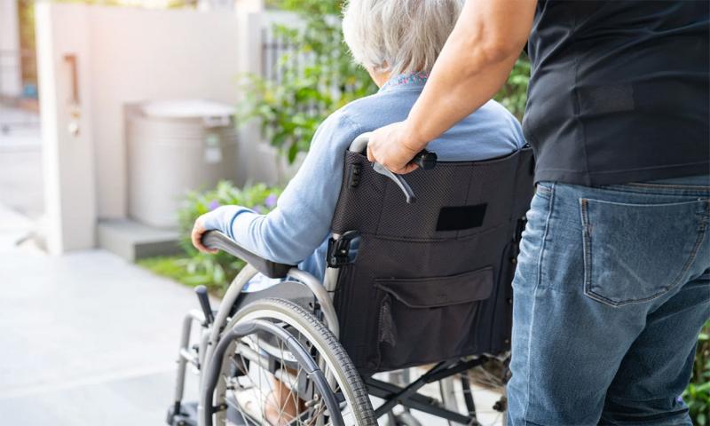 Man pushing an older woman in wheel chair.