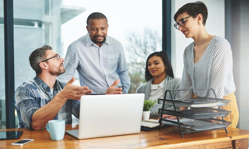 Co-workers having a discussion around a laptop.