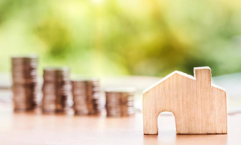 Wooden house with stacks of coins in the background.