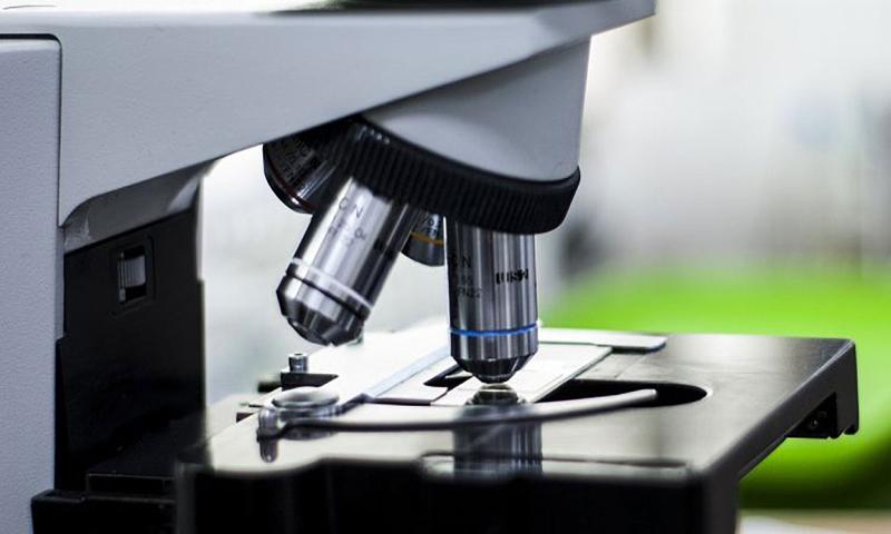 Microscope analyzing a glass slide.