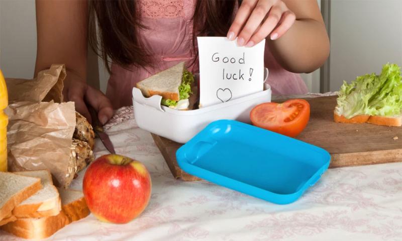 Mother placing a good luck note in her child’s lunchbox.