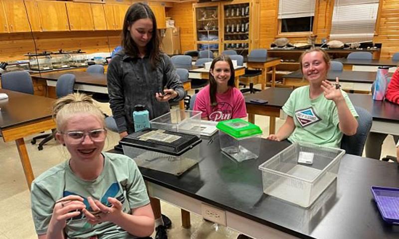 Youth observing different types of snakes in a classroom.
