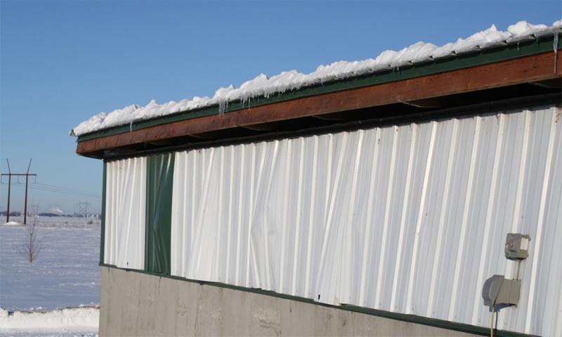 Pole barn with buckled sides due to snow load on roof.