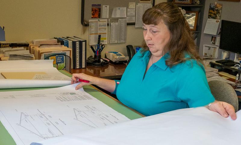 Woman reviewing building plan in a farm office.