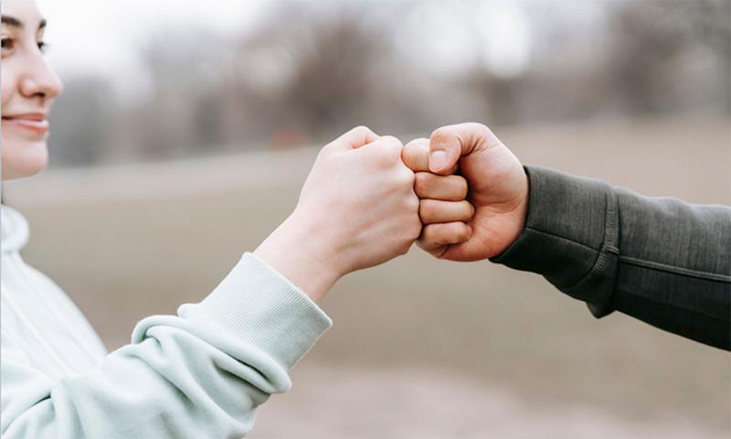 Man and woman bumping fists on a jogging path.
