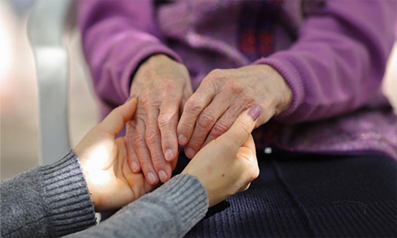 Young woman holding an older woman’s hands.