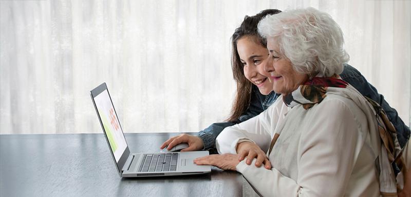 Granddaughter reviewing information on a laptop with her grandmother.