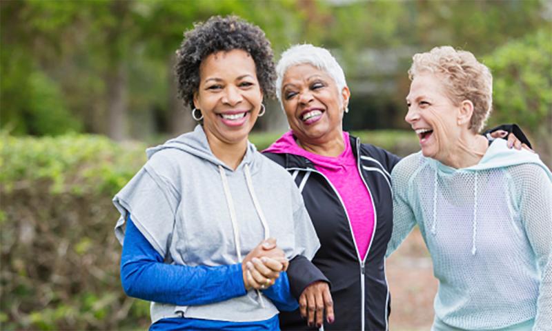 Three older women going for a walk near a park.