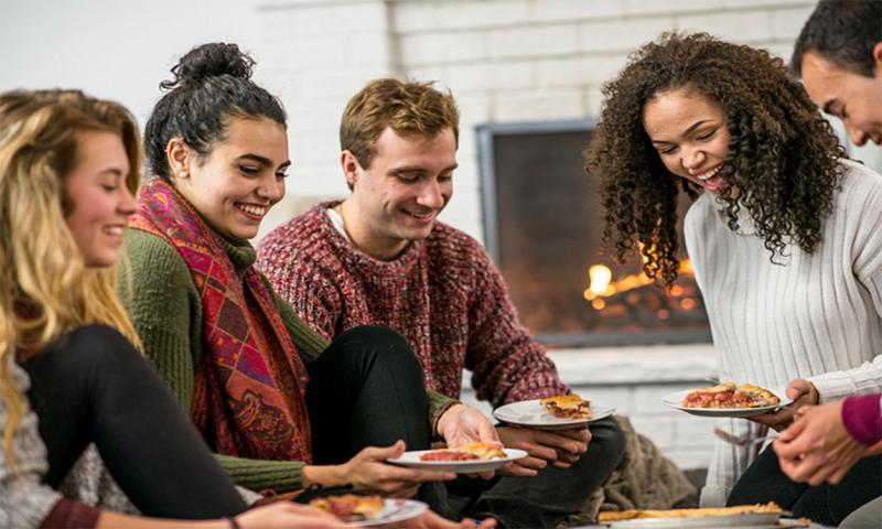 Group of friends enjoying pie by the fireside at a Christmas gathering.