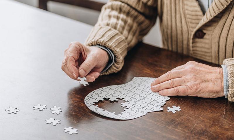 Older adult male putting a puzzle of a human head together.