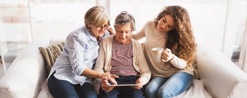Mother and daughter reviewing information on a tablet with grandmother.
