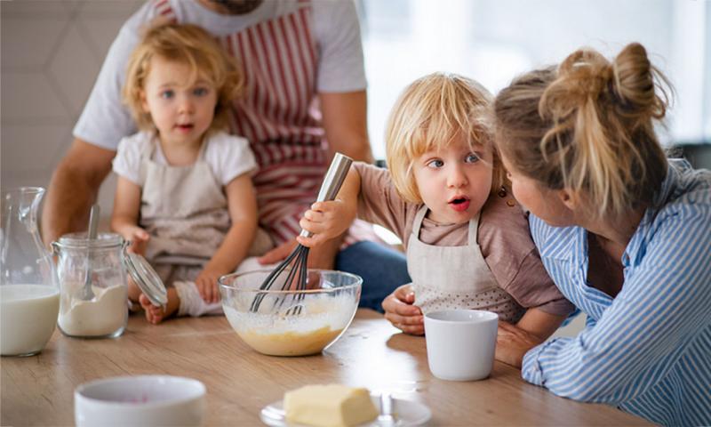 Mother and father giving two young children a cooking lesson.