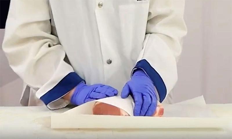 Pork roast being wrapped in white butcher paper.