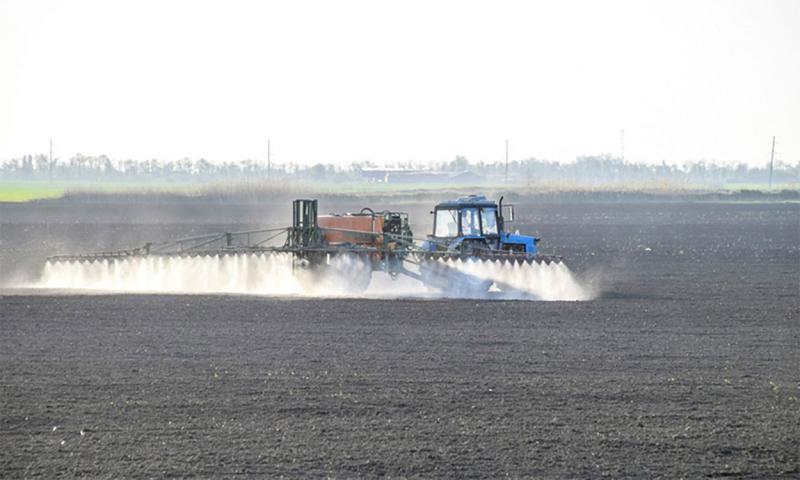 Crop sprayer applying preemergence herbicide to a bare field.