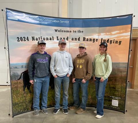 Four people stand in front of a backdrop that says &quot;Welcome to the 2024 Land and Range judging&quot;